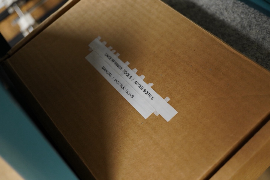 An Underpinner with two dissembled ‘arms’ and a box containing tools, accessories and manual